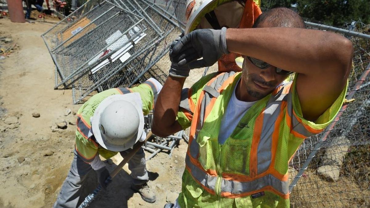 Frank Smith wipes away the sweat in the Friday midday heat. Smith and other Valverde Construction workers were installing new manhole covers along H Street under the Highway 180 overpass, part of the high-speed rail project.