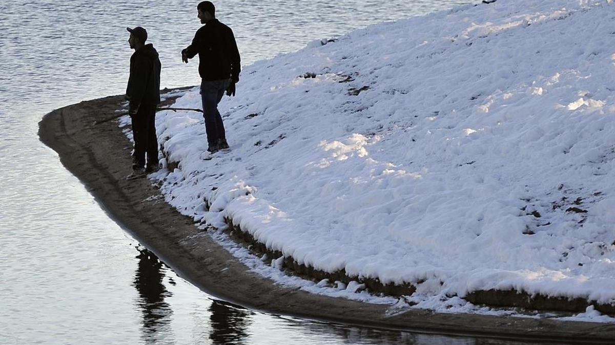Two men look out over Shaver Lake from the snowy shoreline Sunday afternoon.