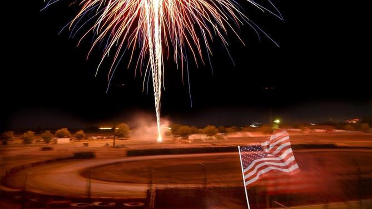 Alanah Clark, 4, and brother Jaeden Clark, 7, center, wave their flags with mom, Eliza Clark, right, under a colorful fireworks burst, during the Red, White & BOOM Fireworks Festival put on the Chowchilla Lions Club at the Chowchilla Fairgrounds, Saturday night, July 2, 2016.