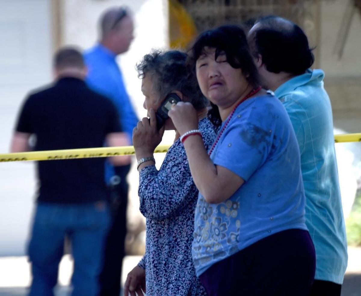 With a bloody handprint on her shoulder, a family member of a shooting victim, with other relatives, head to meet with a Fresno police chaplain after a shooting at 5267 E. Hammond Ave. in east-central Fresno on Tuesday morning, June 6, 2017. Police said four people were shot; three are dead.