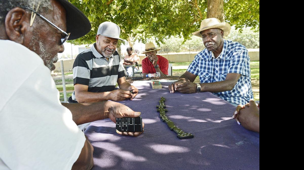 
On a mild summer day Wednesday in Fresno, Conway Wade, right in straw hat, and James Cole, in striped shirt, join neighborhood friends in a game of dominoes below the shade trees at Pride Park in west Fresno. The friends get together about everyday, they say, to engage in the friendly game and exchange some good-natured banter.
