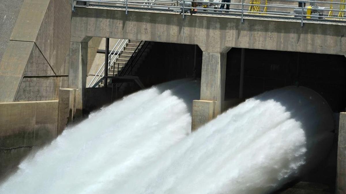 Dwarfed by the thunderous roar of releases of Millerton Lake water – from a pair of huge Friant Dam valves – totaling 1,000 cubic feet per second, Michael Wolfe, left, Friant Dam supervisor of hydrologic technicians, and Darrin Williams, Friant Dam maintenence supervisor, observe the historic release, Tuesday afternoon.