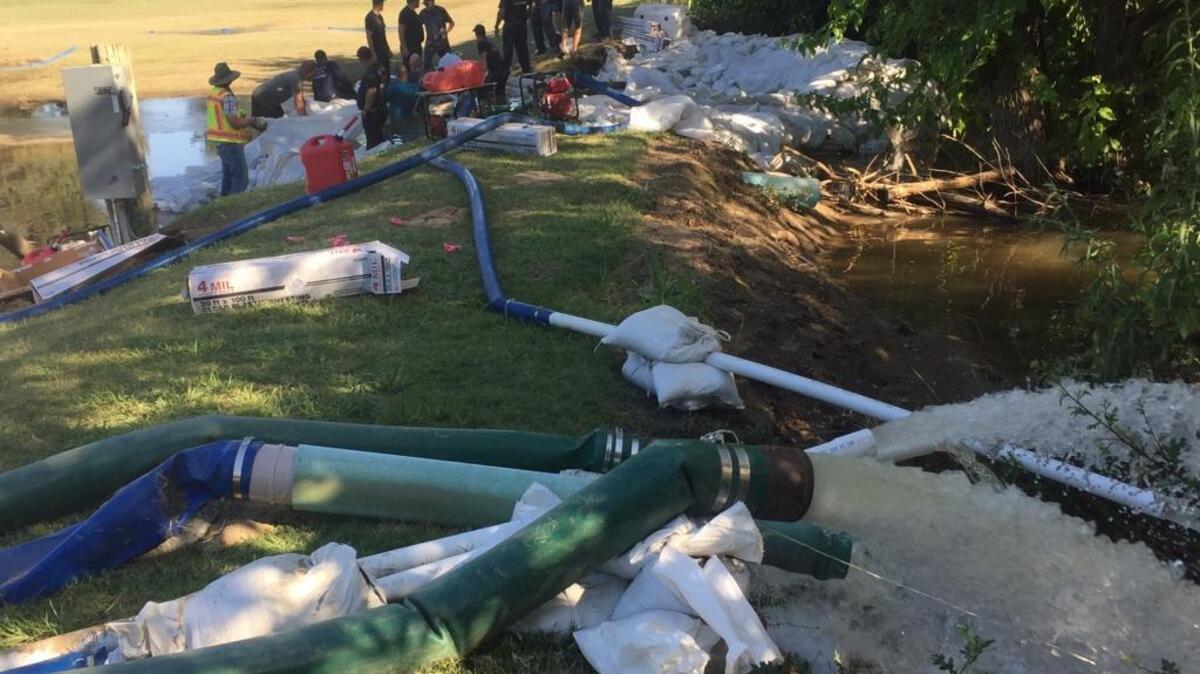 Tulare County Fire Department crews put in more sandbags at a breach of the Kings River at the Kings River Golf and Country Club as a pump removes water from a fairway.
