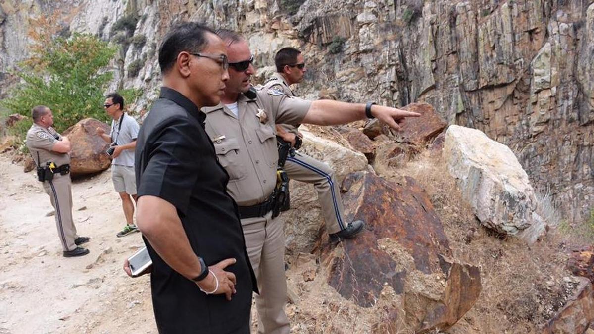A Thai official confers with a California Highway Patrol trooper about a crashed car in the Kings River that may contain two missing Thai tourists.