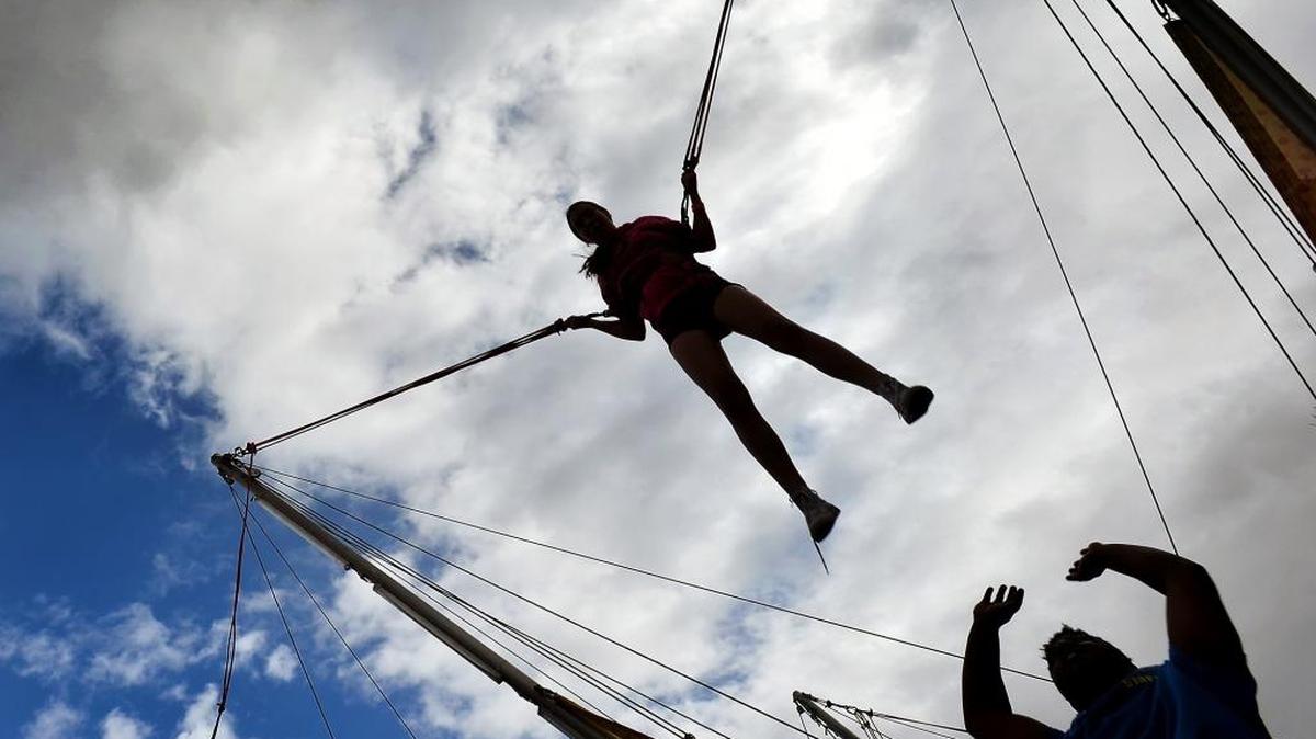 Paige Haworth, 13, Hanford, gets a little help while jumping on the Turbo Jump ride under partly cloudy skies and blustering winds at the Big Fresno Fair on Sunday, Oct. 16, in Fresno.