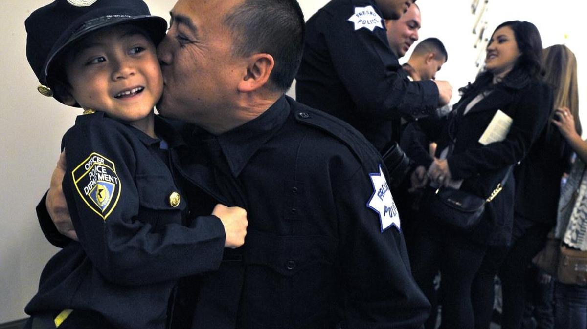 In his little policeman uniform, proud 6-year-old Damon Nguyen gets a smooch and hug from his dad, new Fresno police officer Phu Nguyen, after a swearing-in ceremony on Monday morning, Feb. 8, 2016, at City Hall. Nguyen was one of 11 new officers along with four Police Cadets and two administrative clerks.