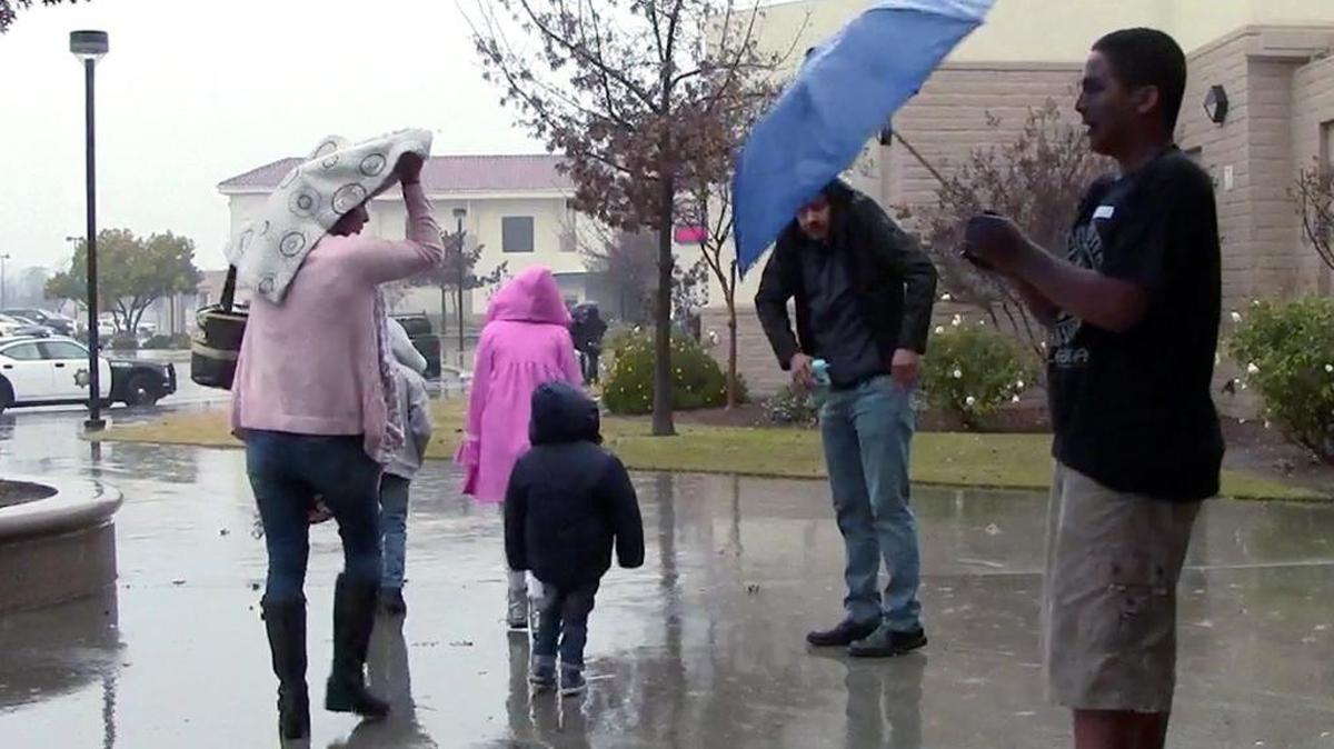Families shield themselves from the morning rain as they arrive for Cornerstone Church’s annual giveaway and Christmas celebration held at Sunnyside High School in Fresno on Saturday.