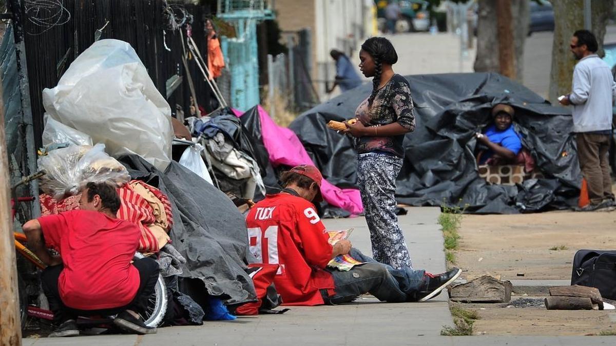 Homeless people congregate on F Street near the Poverello House in April. A growing number of complaints from residents and businesses about homeless encampments is spawning a proposal to ban chronic camping.