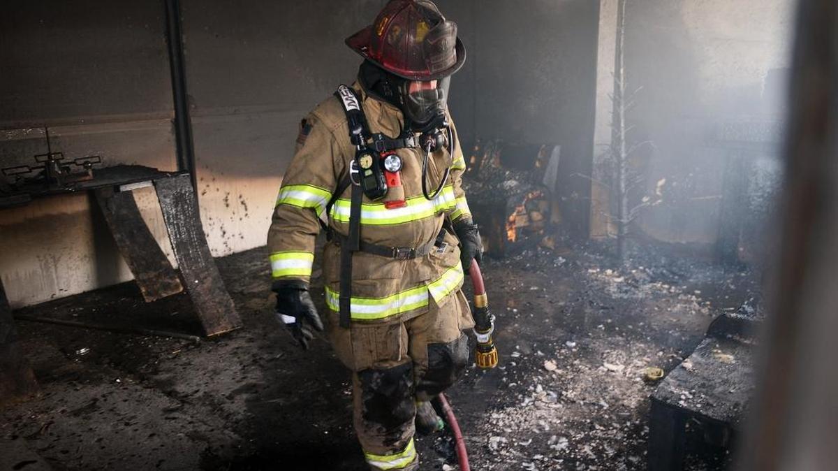Fresno Fire Capt. Kevin Reynolds walks out of a charred fire training room that had been filled with Christmas trees, wrapped gifts and decorations and lit on fire to show show how a dry, improperly maintained tree can instantly turn the inside of a home into an inferno on Wednesday, Dec. 14, 2016.