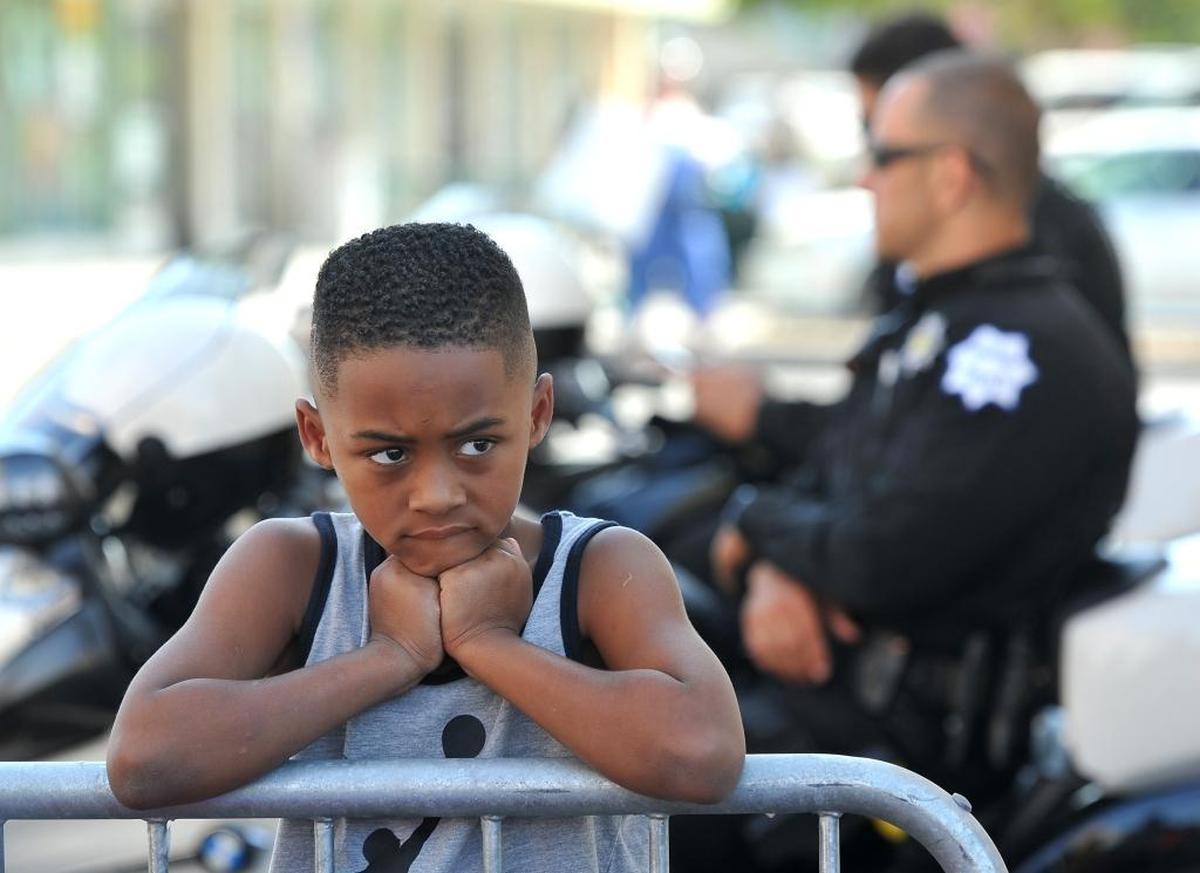 Ryan Dixon, 6, watches the “Fresno’s Counter Rally Against Hate,” at Olive and Wishon avenues in the Tower District, as Fresno police motorcycle officers keep watch on an alley Saturday morning, Aug. 26, 2017.