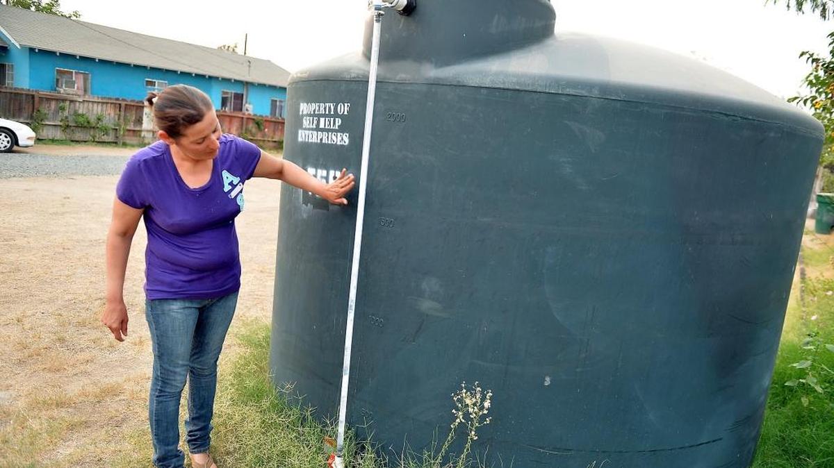 Aida Beltran, 41, checks the water level of the county tank of water in her front yard in East Portervilleon Sept. 9, 2015. The family is now enduring the drought after their well went dry a year ago.