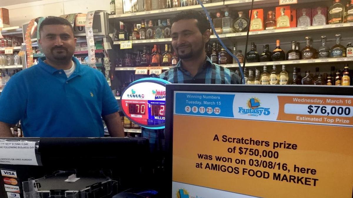 Amigos Food Market manager Maged Abdullah, left, and co-worker Antar Saleh smile as an electronic California Lottery sign flashes news about a winning $750,000 scratcher ticket that was sold at the southeast Fresno store last week.