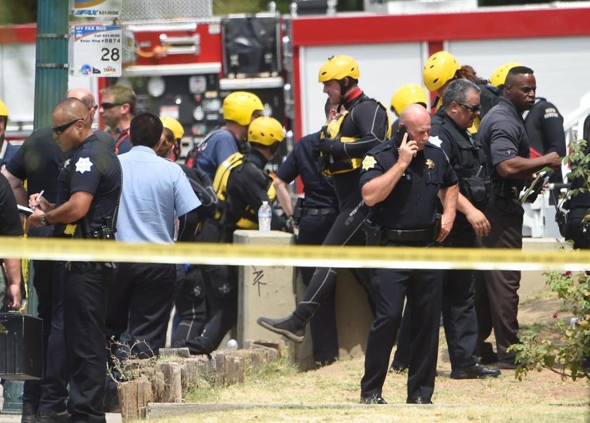 Fresno Police Chief Jerry Dyer is updated while on the scene of the recovery of a body from a canal, underway in background, on Van Ness Avenue in central Fresno, Saturday, Aug. 6.