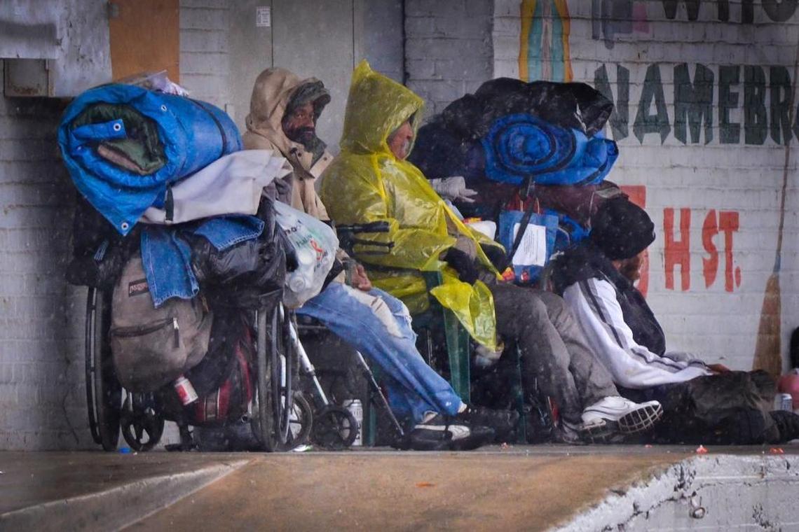 A trio seeks shelter from a storm under the awning of a Ventura Street business in downtown Fresno in this file photo. A new partnership between the city and the county aims to tackle Fresno’s homelessness crisis as a united front.