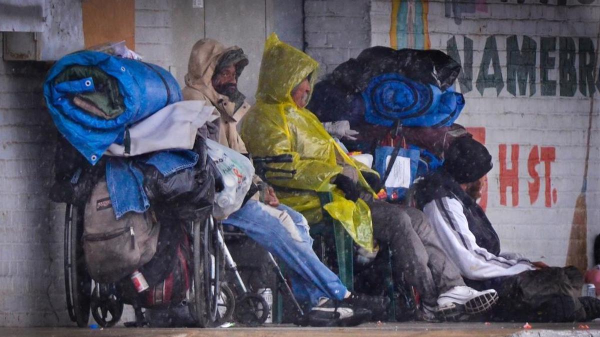A trio of homeless seek shelter from a storm under the awning of a Ventura Street business in downtown Fresno in this file photo. A new city ordinance proposed Aug. 29, 2024, would allow busineses to call police to remove trespassers who refuse to leave when asked to move.