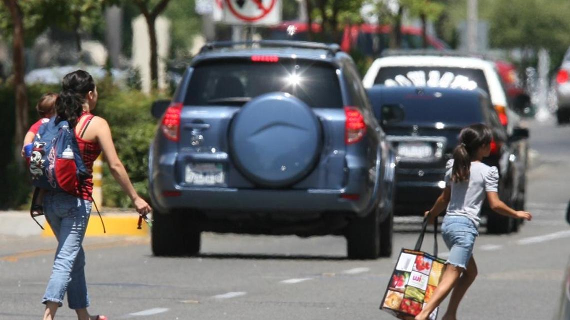 Pedestrians jaywalk across Tulare Street amidst traffic downtown Fresno in October 2016.