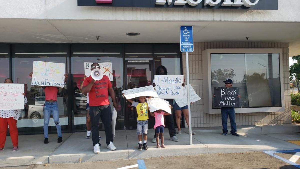 Rev. Floyd Harris uses a bullhorn as he recounts what happened to Dorian Johnson and his uncle the day they were detained at the T-Mobile store by police after a false robbery call.