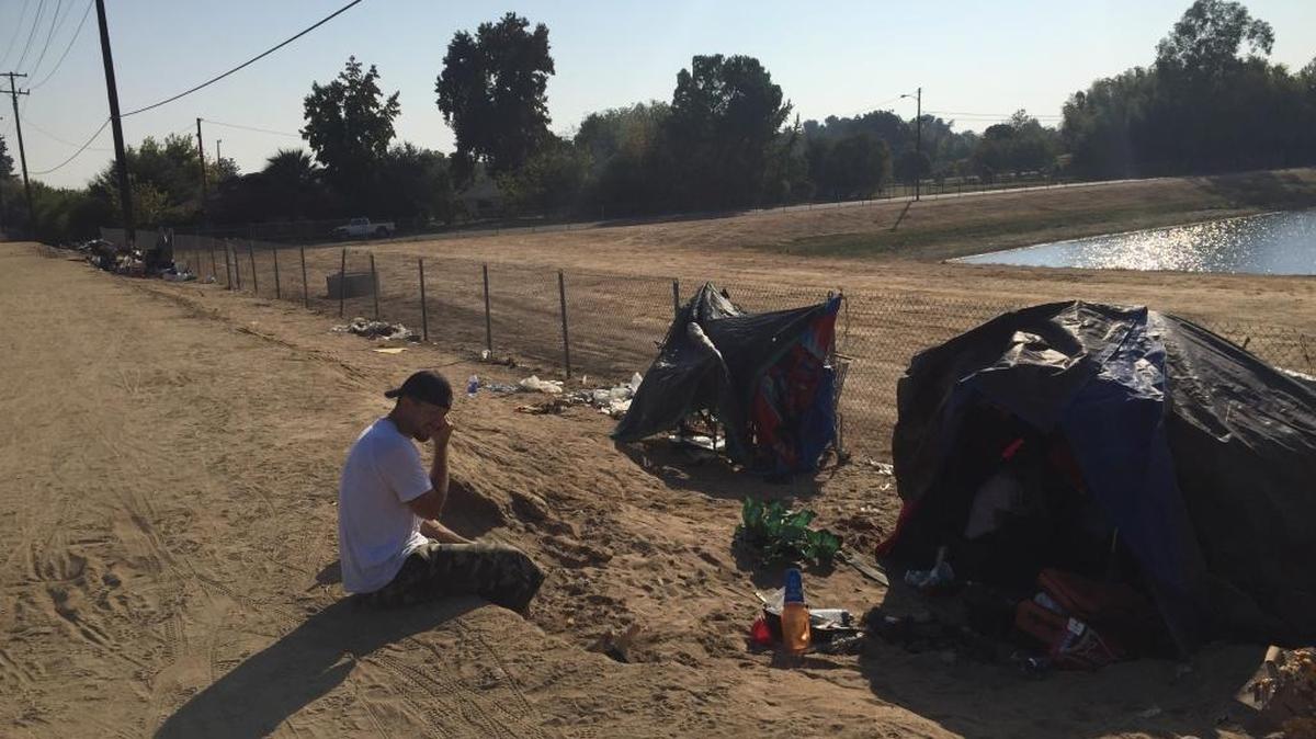 A man who identified himself as William Morgan waits near his tent at a homeless encampment near Millbrook and McKinley avenues in central Fresno. Police were sent to the camp Wednesday to enforce the city’s ban on camping.