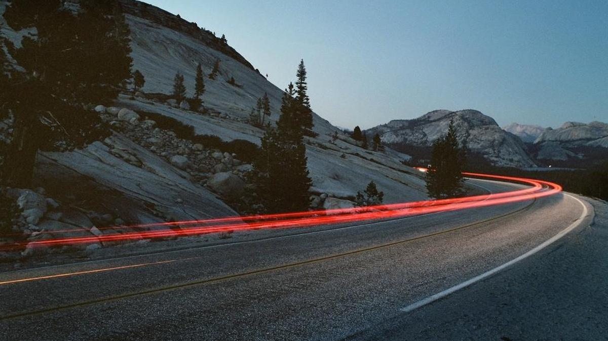 Like rings of Saturn, traffic passes Olmstead Point at dusk, moving eastward along the Tioga Pass Road towards Tenaya Lake, seen at the far right. Photographed on Friday evening, Sept 16, 2005 in Yosemite National Park. The road is expected to reopen for the summer on Wednesday, May 18, 2016.