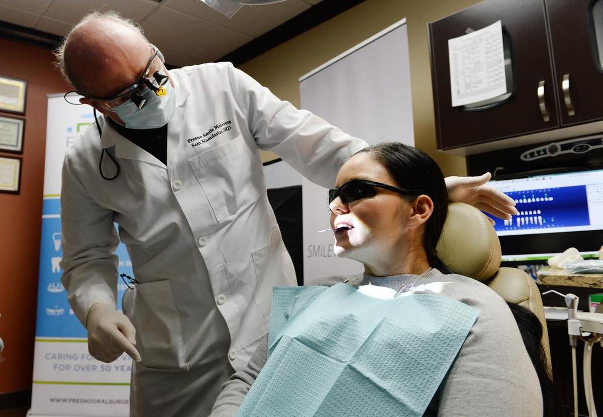 Dr. Sam Namdarian checks the bite of Erlinda Vargas of Fresno after placing her new implant-supported permanent denture at Fresno Smile Makeovers in Fresno on Monday, March 4, 2019. Vargas is the first recipient of the Fresno Oral Maxillofacial Surgery & Dental Implant Center’s Second Chance program to help people with extensive tooth loss and other oral health issues but who are unable to afford proper treatment. Vargas suffered through domestic abuse in her family as a child and did not receive proper dental care, which led to her oral health issues.