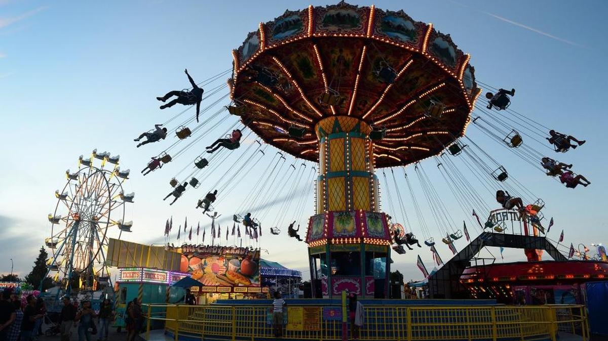 The sun sets as the swing ride glides riders through the evening air in the carnival area at the Big Fresno Fair last year. This year’s fair runs from Oct. 4-15.