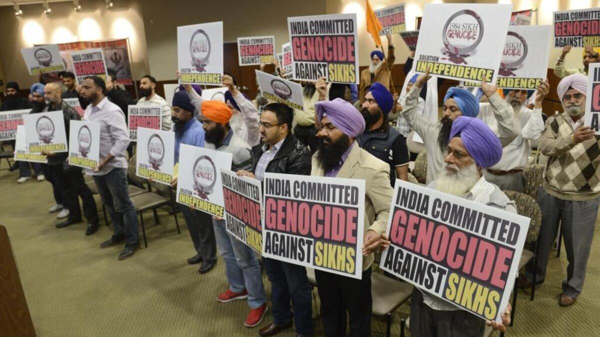 Members of the Sikh community hold up signs denouncing the mass killing of Sikh people in India in 1984, following a vote by the Kerman city council to formally acknowledge the violence as a genocide. The council voted unanimously to pass the resolution.