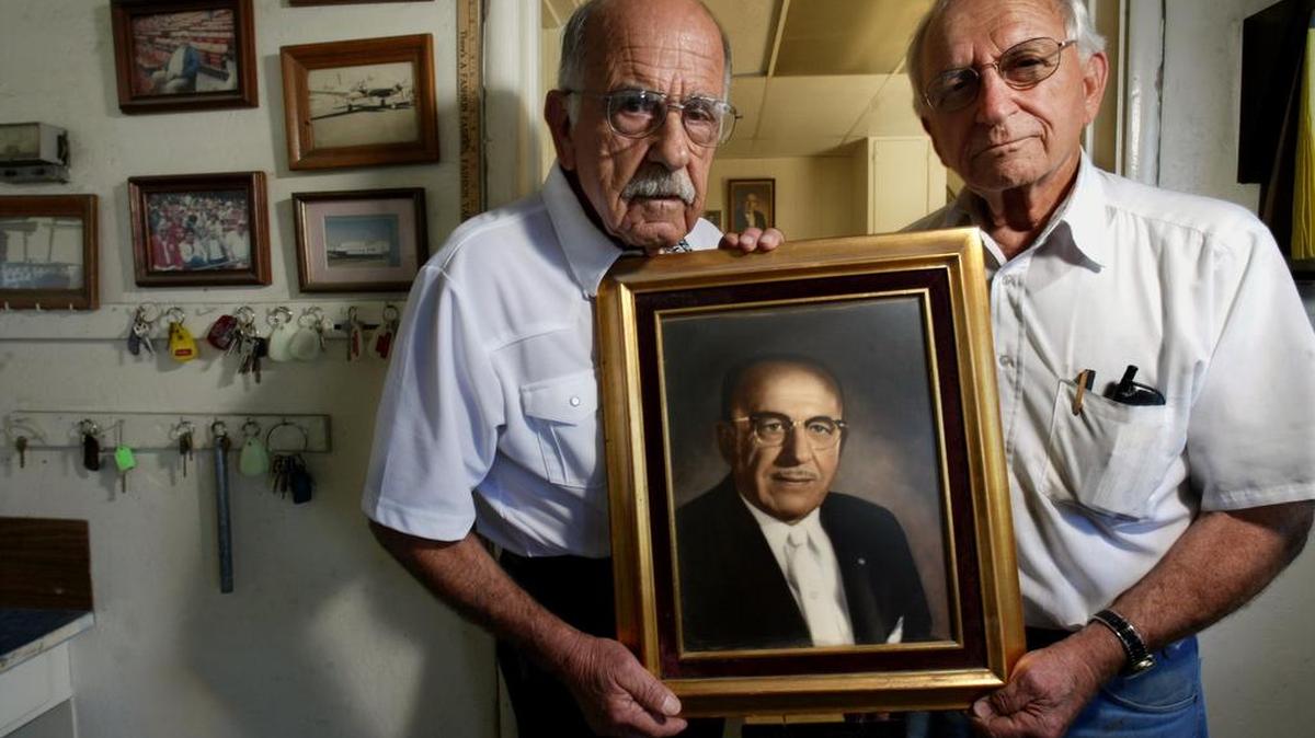George Bedrosian Sr., right and his brother Peter hold a portrait of their father Avedis Bedrosian inside the Bedrosian Truck Service office in a 2003 photo.
