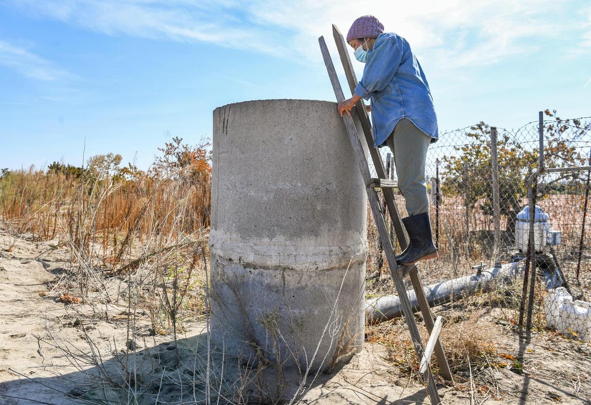 June Moua looks to see how the groundwater pump is working on her small farm west of Fowler on Tuesday, Oct. 19, 2021.
