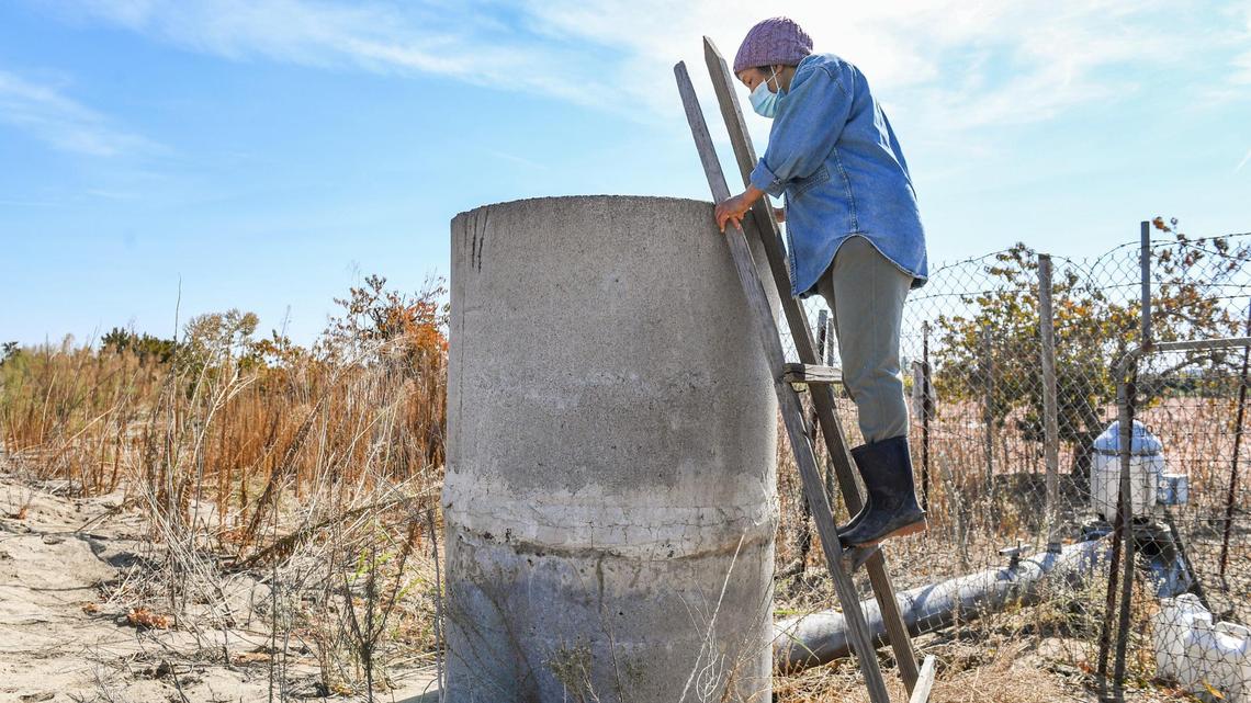 June Moua looks to see how the groundwater pump is working on her small farm west of Fowler on Tuesday, Oct. 19, 2021.