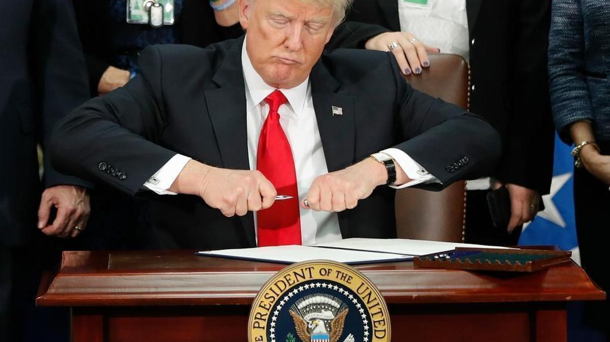 President Donald Trump takes the cap off a pen before signing an executive order for immigration actions to build a border wall during a visit to the Homeland Security Department in Washington, D.C., on Wednesday.
