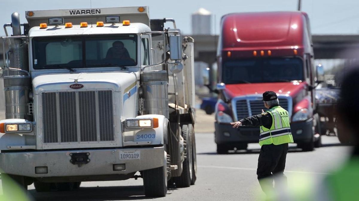 Inspector Ching Yang of the California Air Resources Board, directs trucks in for inspection on North Avenue near Highway 99 on June 14, 2016.The San Joaquin Valley Air Pollution Control District wants stricter federal rules on diesel trucks and their emissions.