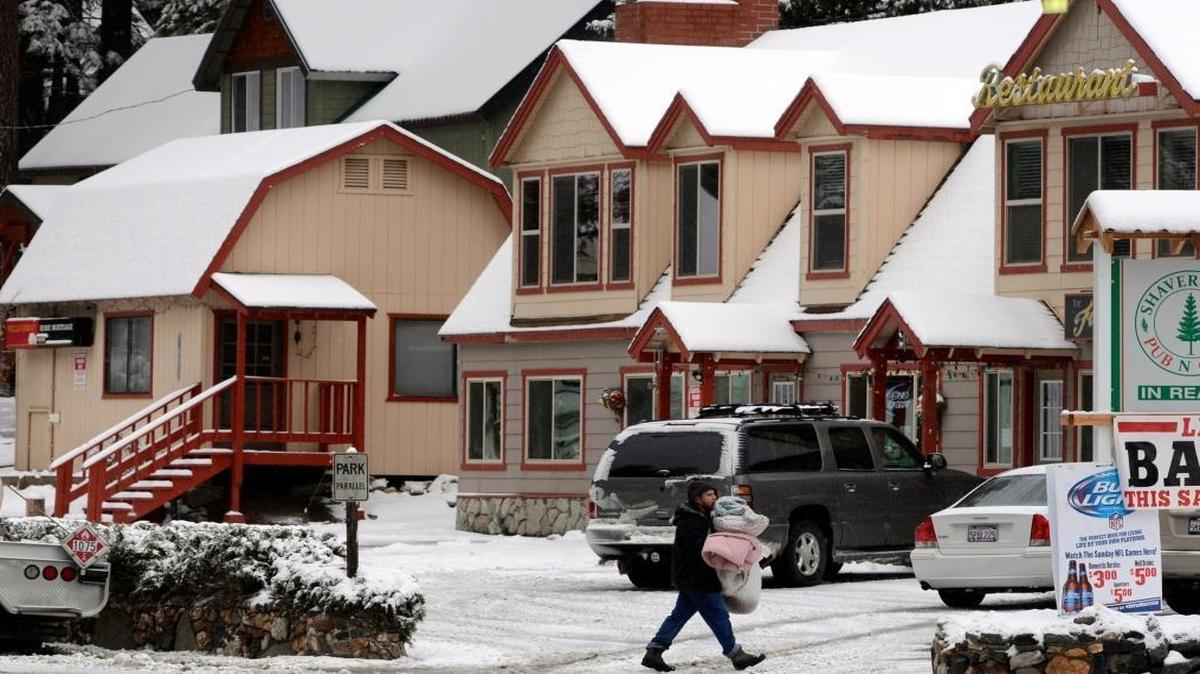 A man stocks up on blankets in the snowy scene earlier this fall in Shaver Lake village. The mountain town will receive more snow later this week.