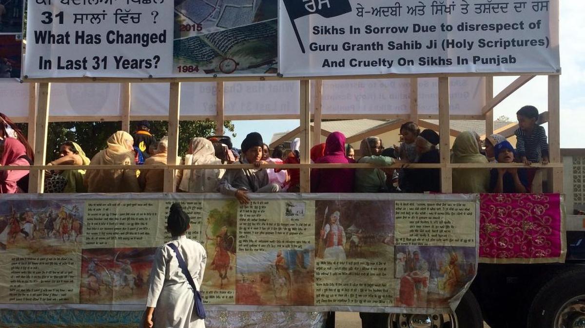 A Sikh boy reads banners adorning parade floats in Fowler during the recent fifth annual celebration of the religion’s founder Guru Nanak’s birthday. The banners reference violence in Punjab since June and questions what has changed since thousands of Sikh civilians were killed starting in 1984.