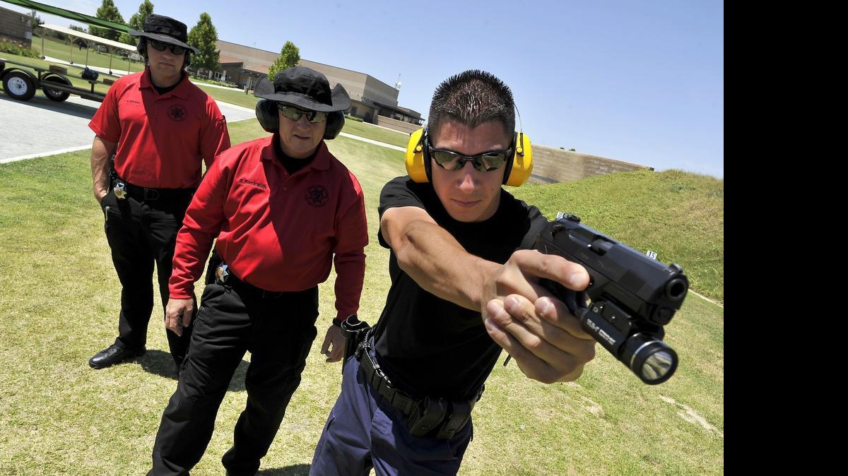 
Fresno Police Sgt. Rob Beckwith, center, reviews the shooting position of recruit Anthony Tafoya, at the Fresno Police Department Regional Training Center, as officer Keith Dooms, left, looks on. 
