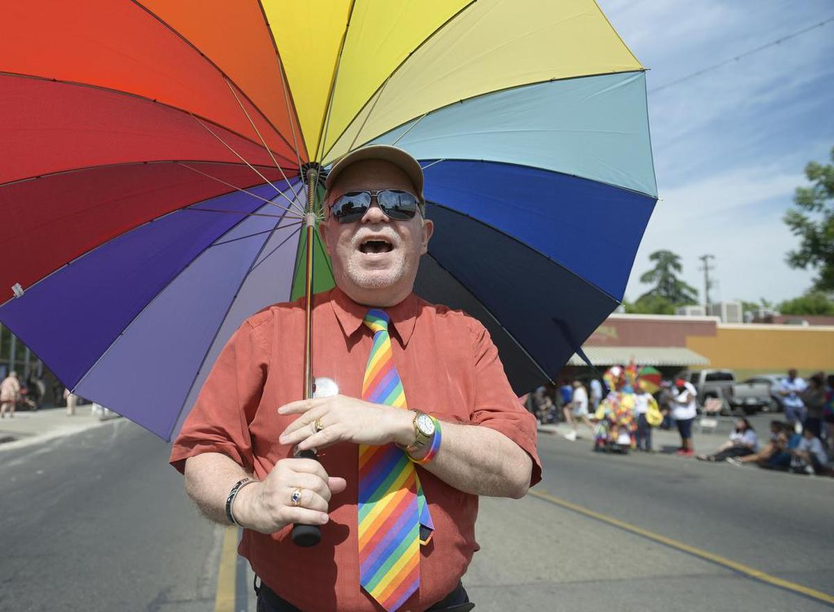 Gay rights activist Slide Childers, one of four parade grand marshals, keeps cool with a rainbow umbrella while marching in the parade at the 26th Pride Parade and Festival in Fresno Tower District, Saturday, June 4, 2016.