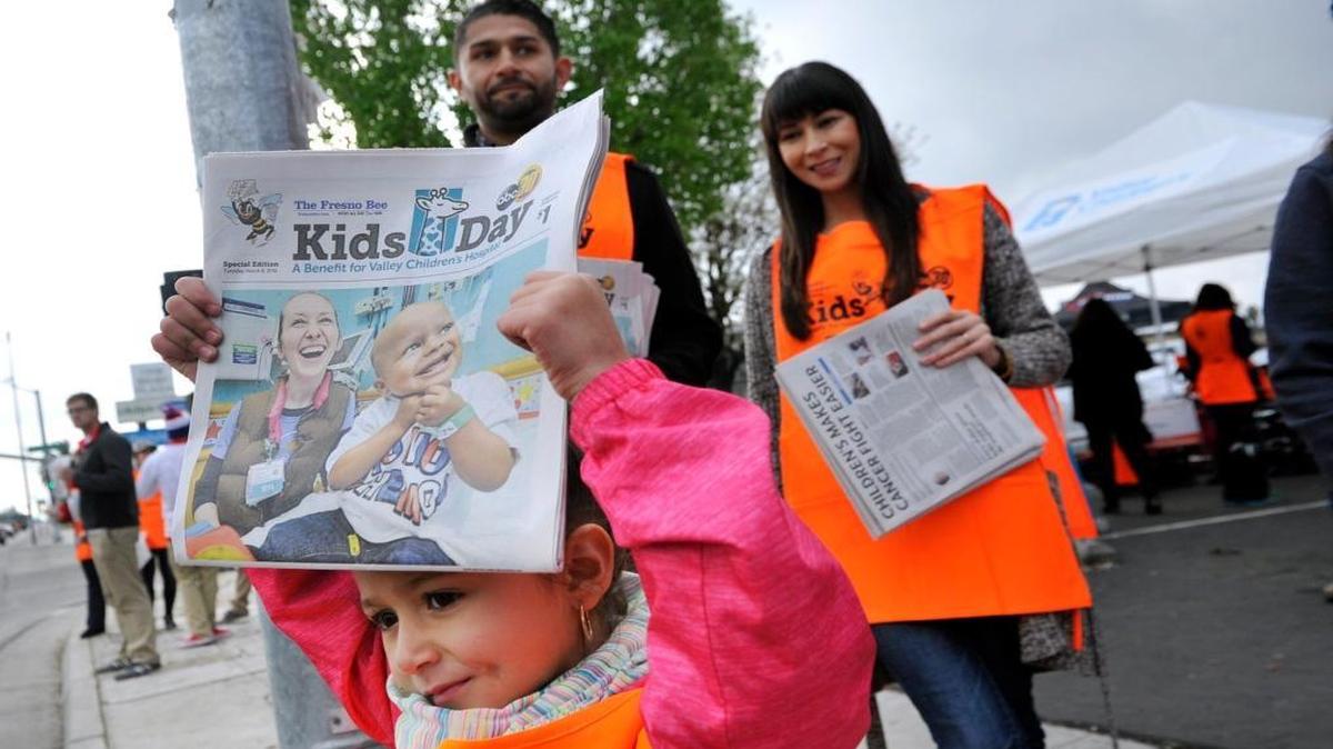 Naima Gutierrez, 5, who has been cancer-free for three years, stands with her parents Pablo, left, and Jessica Gutierrez as she sell Kids Day papers at Celebrity Corner on Blackstone and Shaw Avenue March 8.