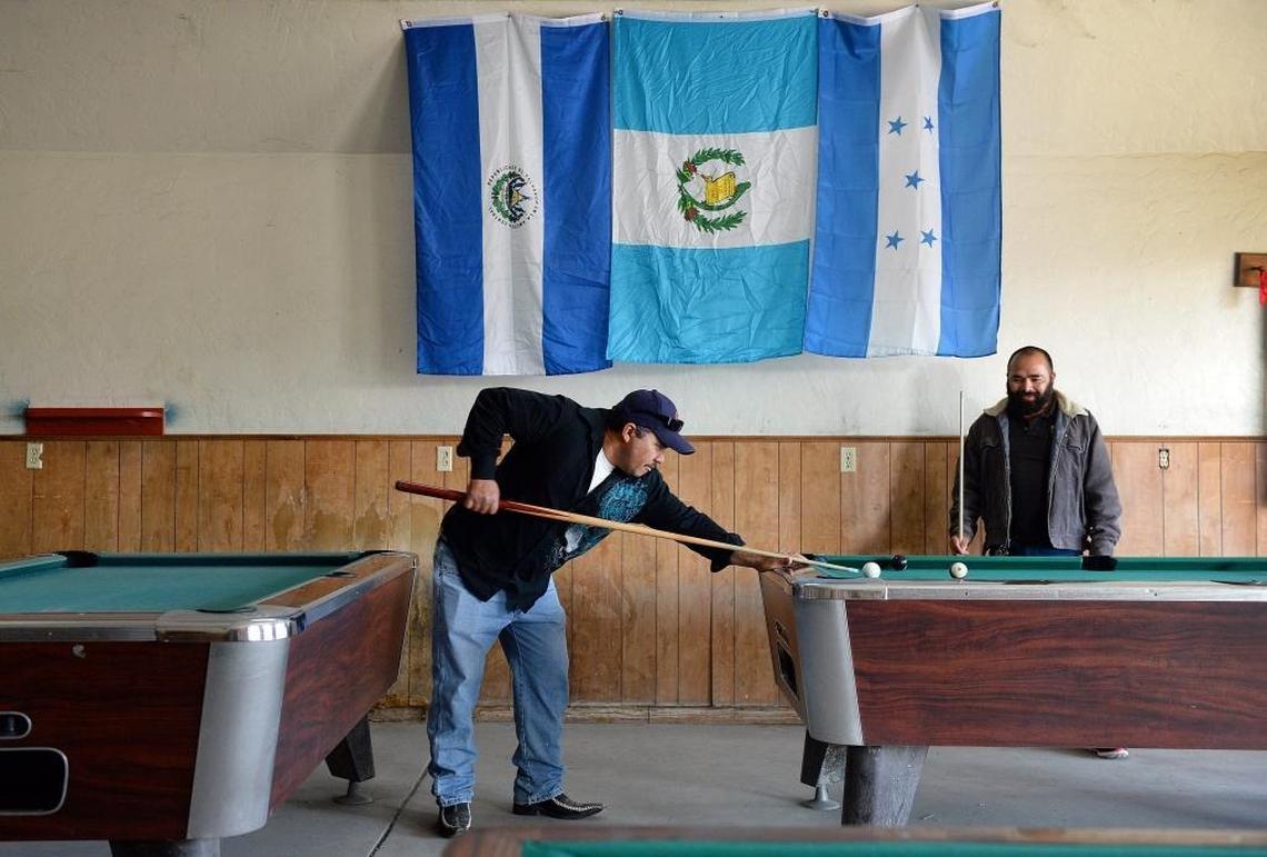 Mendota residents Jose Velasquez, left, and Oscar Lopez, both Salvadoran immigrants, play billiards below the flags of El Salvador, from left, Guatemala, and Honduras at Westside Pool Hall in Mendota on Friday, Jan. 12, 2018. Mendota city officials say that over half of the city’s residents have Salvadoran roots. Many of those are recipients of a temporary protection from deportation, a program Trump announced will end this week.