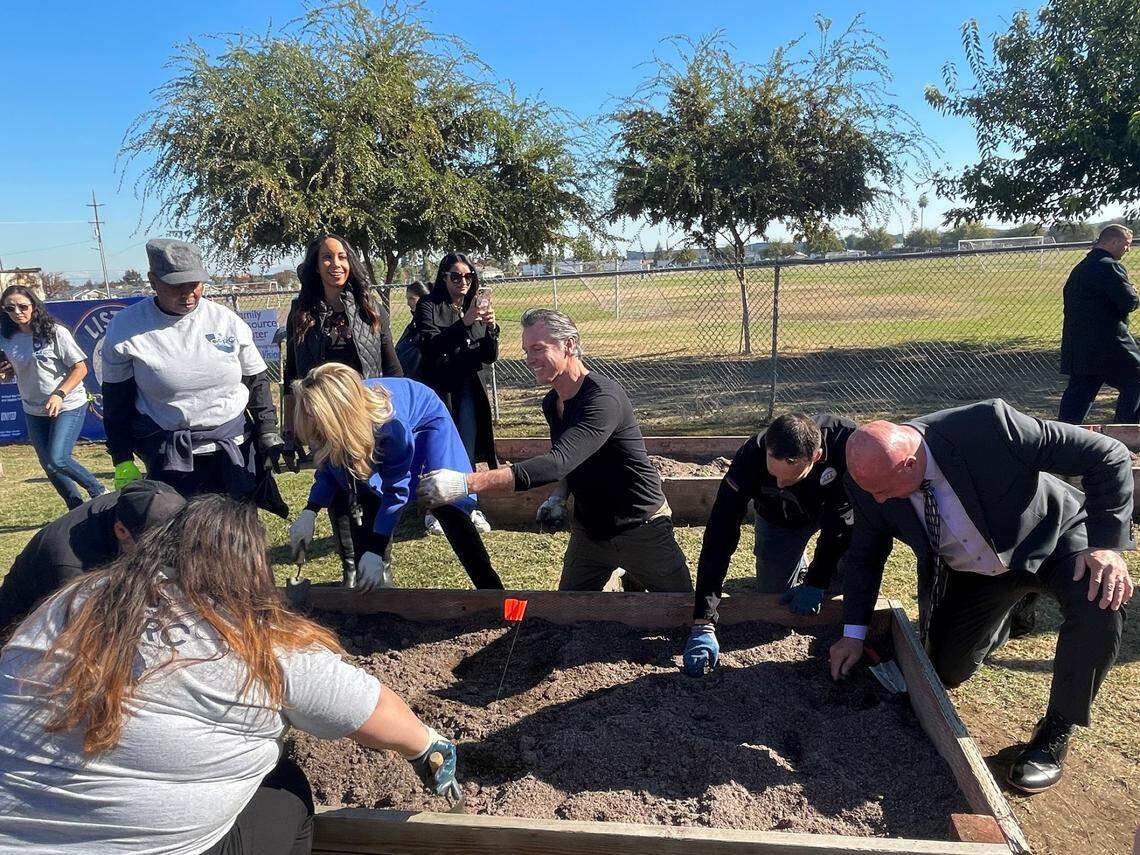 California Governor Gavin Newsom (center) planted seedlings in garden beds at Mary Ella Brown Community Center in southwest Fresno along with First Partner Jennifer Siebel Newsom (left, blue coat), California’s Chief Service Officer Josh Fryday (right of Newsom), Fresno Mayor Jerry Dyer (further right) and community memberson Thursday, Nov. 10, 2022.