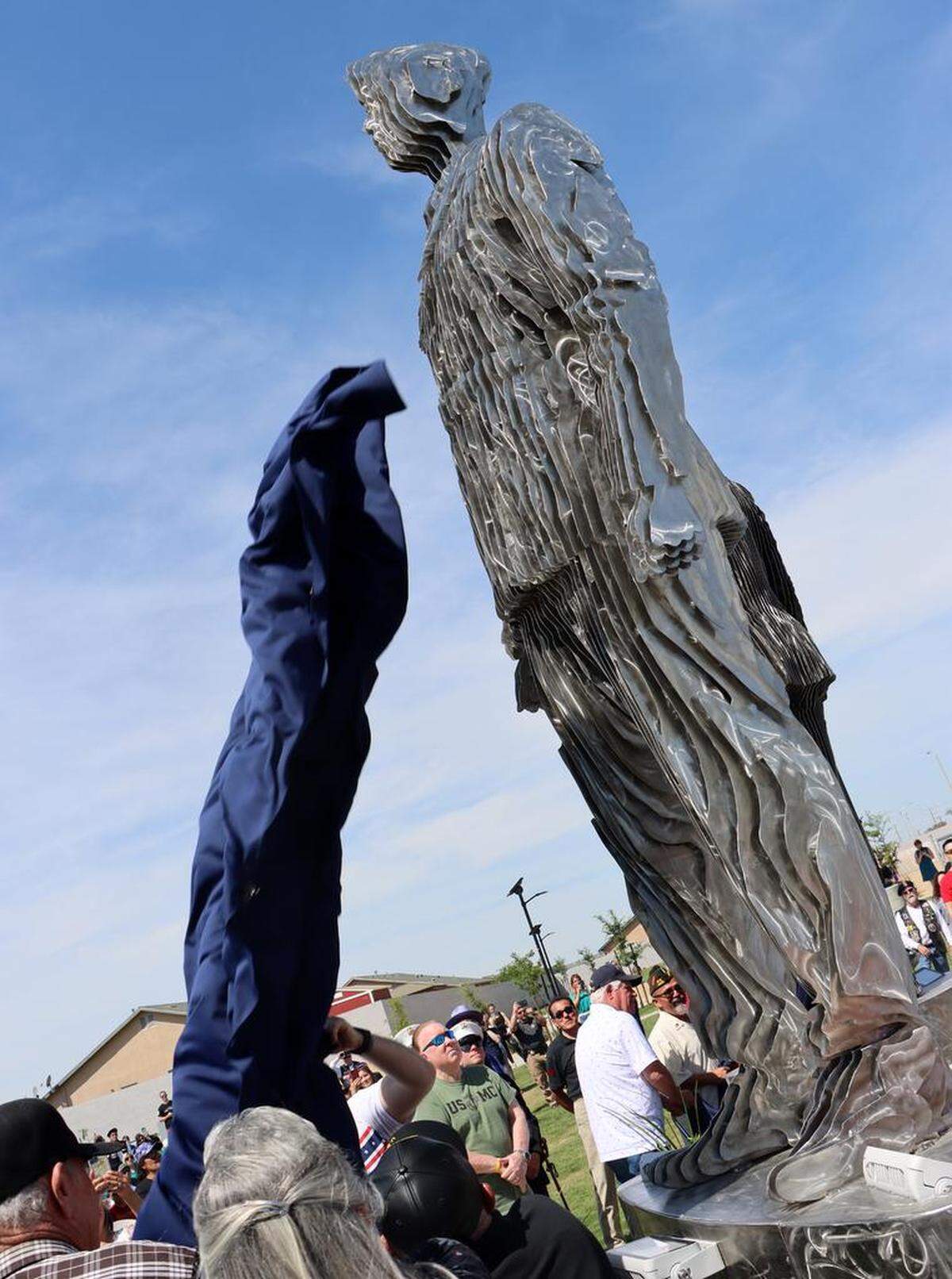 A statue towers over observers during the unveiling of The Five Pillars of Freedom veterans memorial at Gateway Park in Corcoran on April 29, 2023.