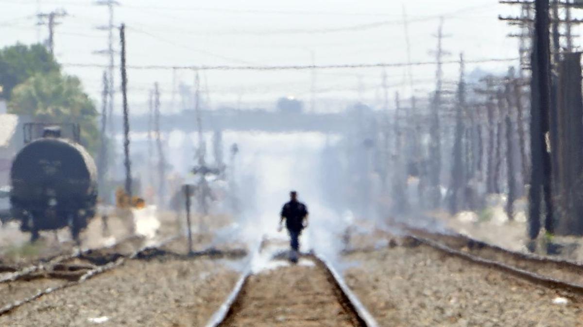 
 Heat waves create a mirage-type appearance of a man walking along the tracks in downtown Fresno.
