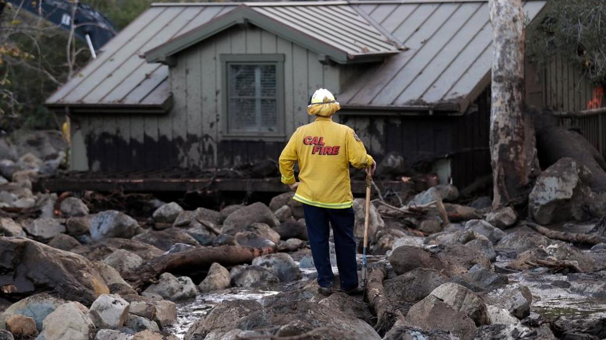A firefighter walks among the rocks and mud left by a mudslide Wednesday, Jan. 10, 2018, in Montecito,