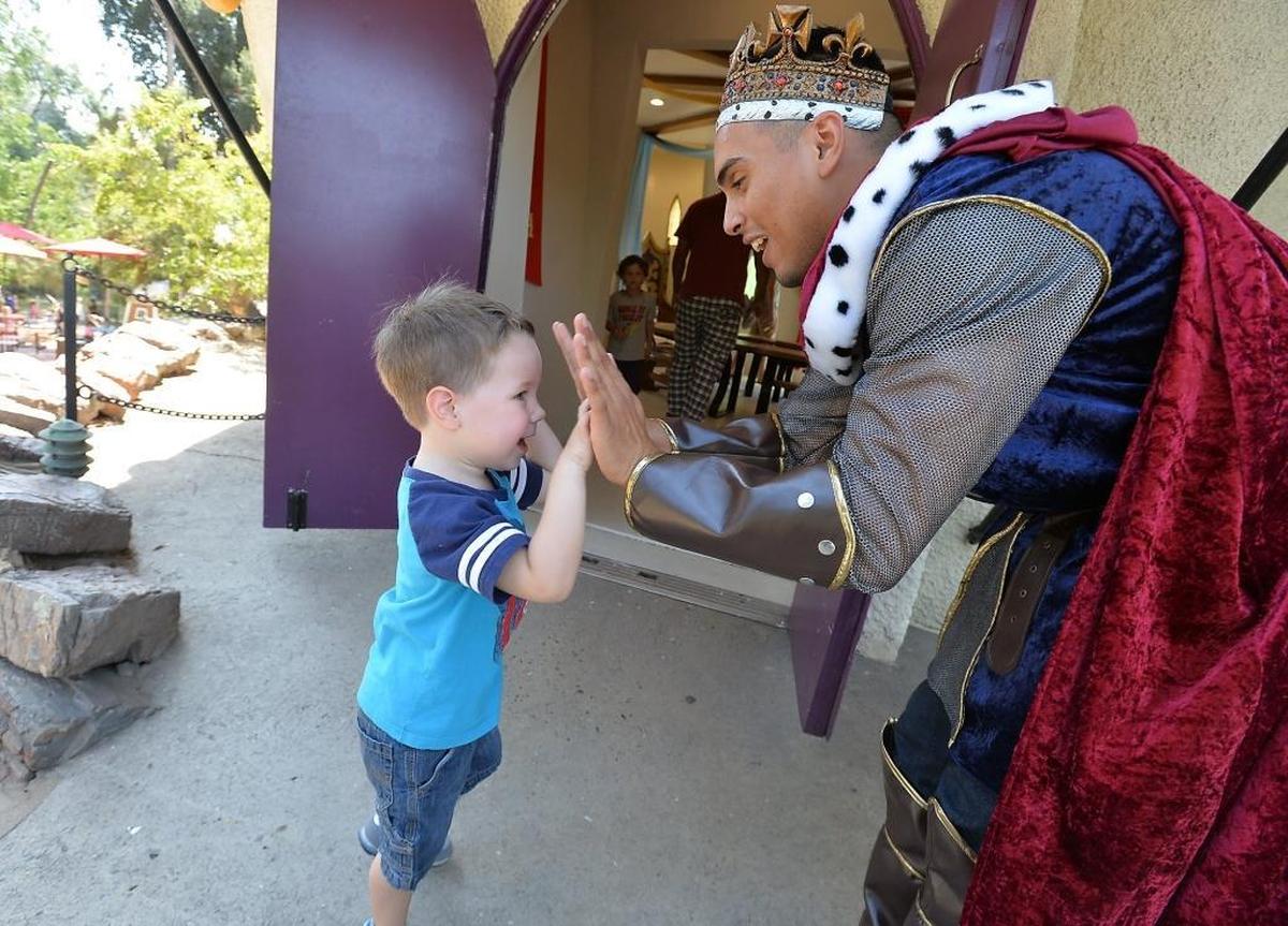 Samuel Emerich, 3, left, of Fresno, high fives with “King Arthur,” Robert Murillo, at the grand reopening of Storyland in Roeding Park in Fresno, California on September 4, 2015.