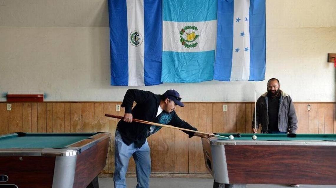 Mendota residents Jose Velasquez, left, and Oscar Lopez, both Salvadoran immigrants, play billiards below the flags of El Salvador, from left, Guatemala, and Honduras at Westside Pool Hall in Mendota. Mendota city officials say that over half of the city’s residents have Salvadoran roots.