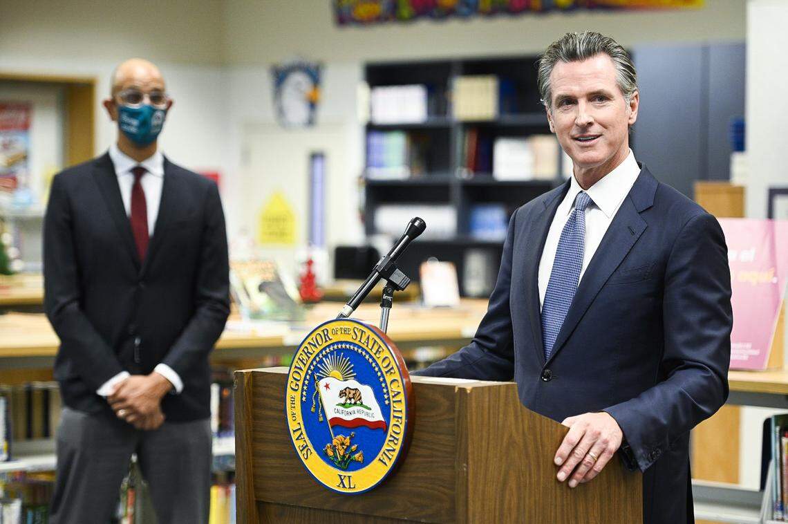 Gov. Gavin Newsom, right, is shown speaking in Winton, California about the confirmation of the omicron variant of COVID-19 in the state. Dr. Mark Ghaly, state Department of Health and Human Services secretary, is shown at left.