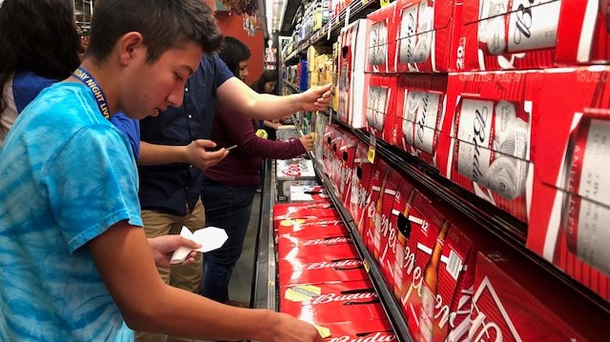 Eber Garcia, a student at Kerman High who is a member of the Youth Leadership Institute chapter of Fresno, works alongside other teens to put stickers on alcohol products to promote awareness of underage drinking at the southeast Fresno Foods Co store on Oct. 28.