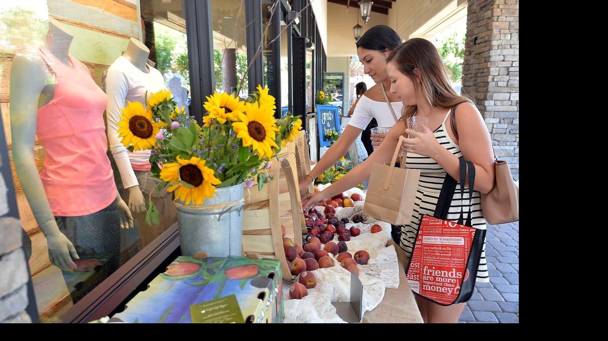 
Elizabeth Carrillo, left, 20, of Clovis, and Haley DeWitt, 18, of Fresno, pick up fresh stone fruit at the lululemon athletica store’s grand opening at Fig Garden Village in Fresno, California on July 3, 2015. The store hosted a live DJ and dance party inside the store in addition to hosting a farmers market outside the store.
