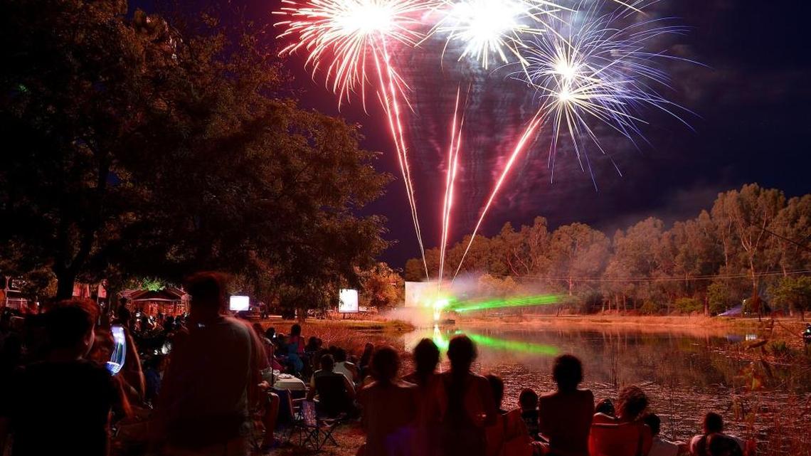 Revelers watch from the banks of a pond at Wild Water Adventure Park in Clovis as fireworks are shot off during the Star Spangled Revue show in 2017.
