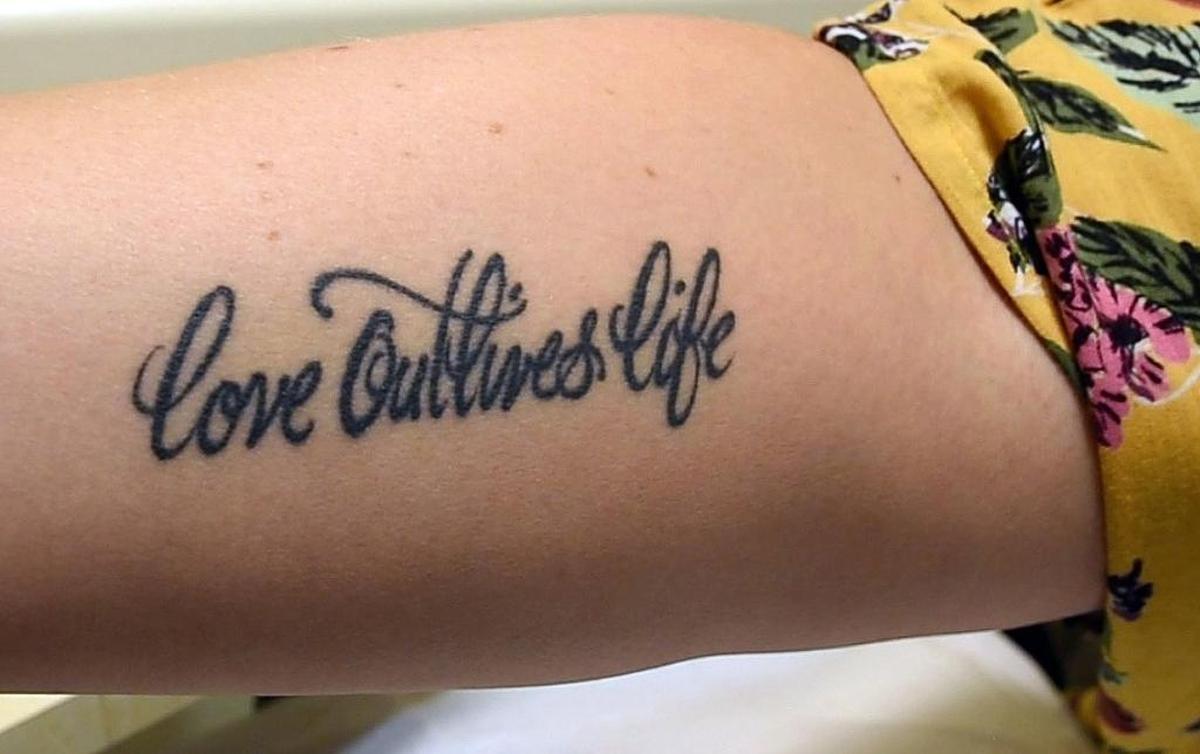 A tattoo on April Doyle’s forearm explains her outlook as she faces metastatic breast cancer, which she recognizes will eventually kill her.