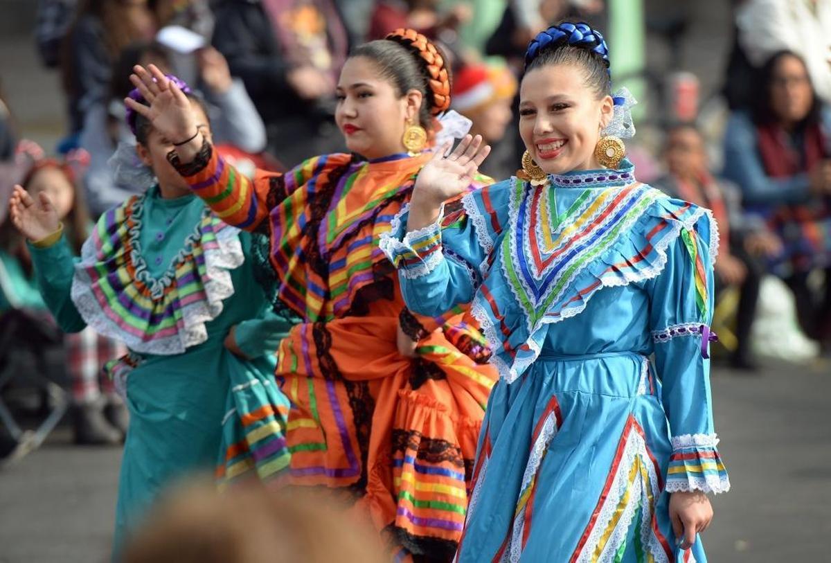 Dancers from Compan’a De Danza El Sol wave while walking in the 88th annual Downtown Fresno Christmas Parade on Fulton Street in downtown Fresno on Saturday, Dec. 2, 2017.