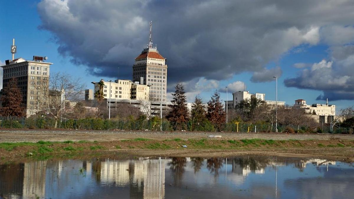 Fresno’s skyline is reflected in standing rainwater from a winter storm in January as clouds passed over downtown, Jan. 7, 2016.